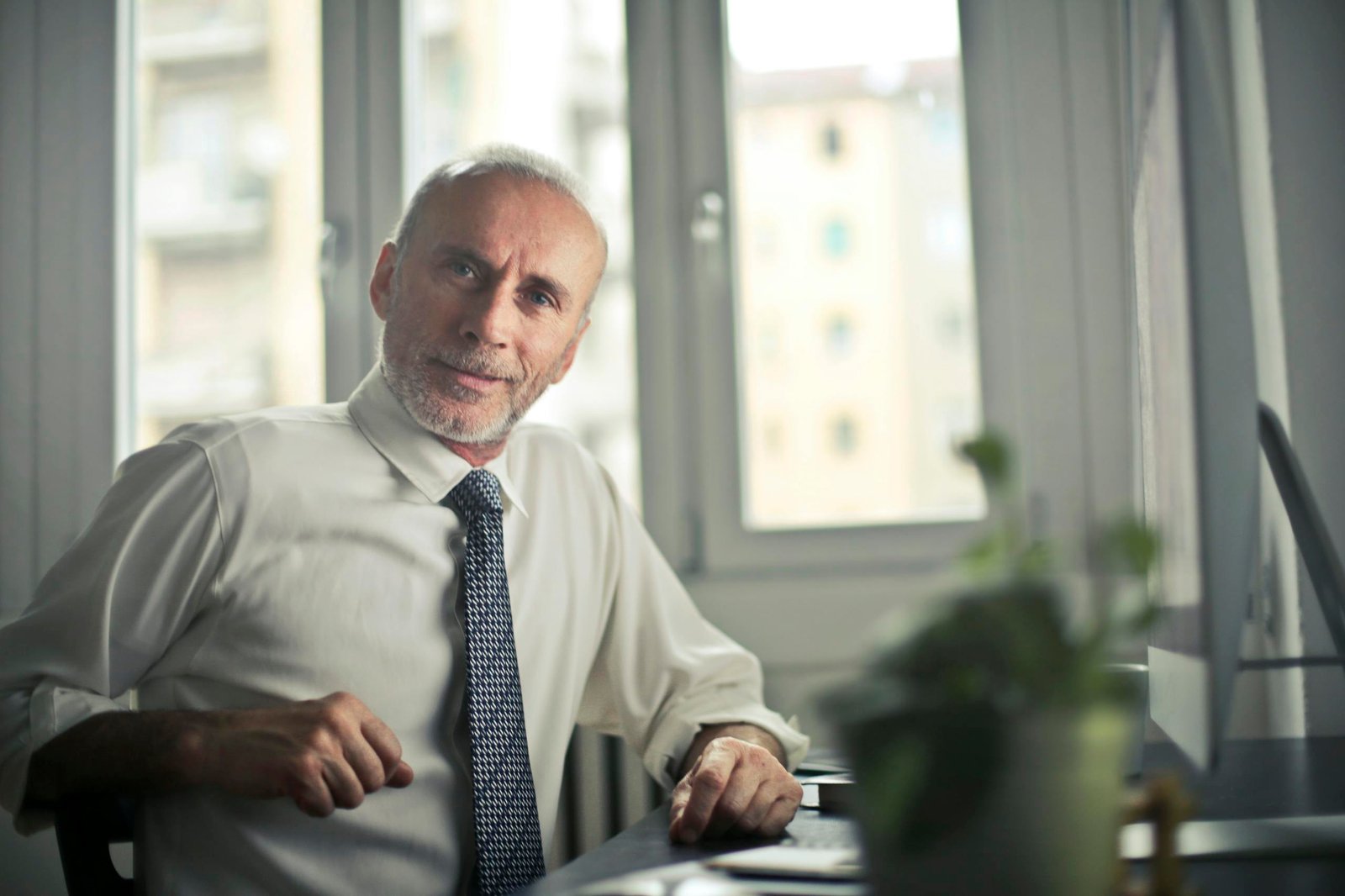 Henkilö A mature man in professional attire smiling in an office setting.
